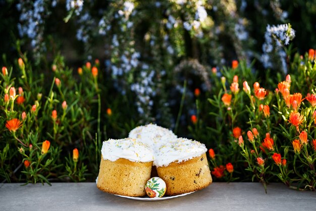 Plate with three easter cakes covered with white glaze in a flower bed