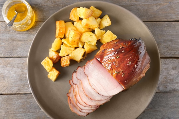 Plate with traditional sliced honey baked ham and potatoes on table