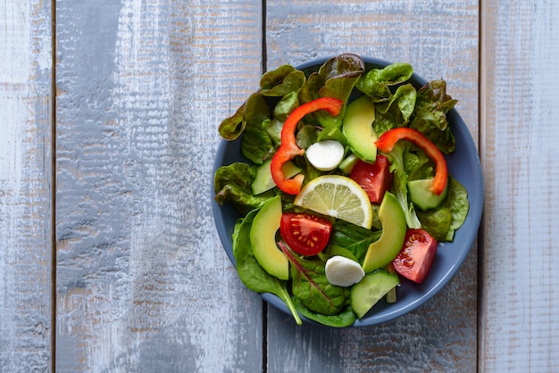 Plate with vegetable salad on rustic wooden background with copy space