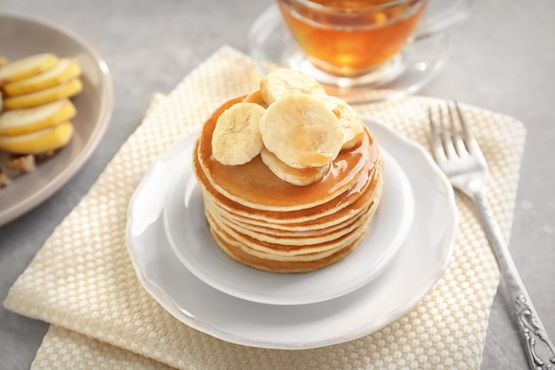 Plate with yummy banana pancakes on kitchen table