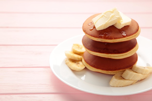 Plate with yummy banana pancakes on pink background Space for text