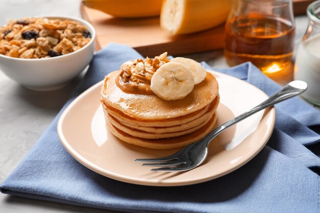 Plate with yummy banana pancakes on table