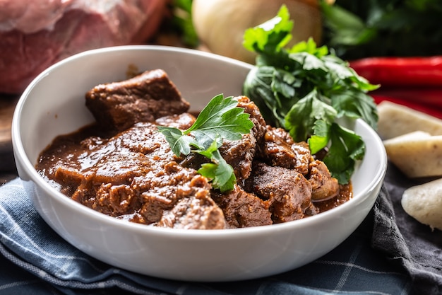 Plateful of of meat stew or a goulash with celery tops.