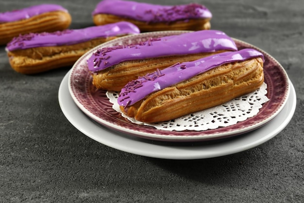 Foto platen met heerlijke geglazuurde eclairs op een donkere achtergrond