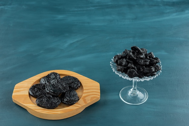 Plates of delicious dried plums placed on blue table.