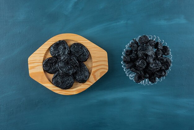 Plates of delicious dried plums placed on blue table.