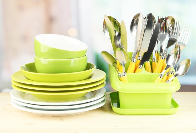 Plates forks knives spoons and other kitchen utensil on bright background