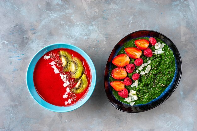 Plates with colorful strawberry and spinach smoothies seeing from above