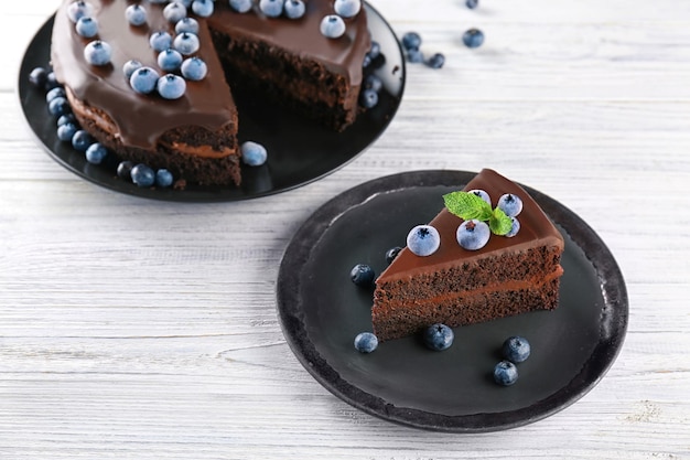 Тарелки с вкусным шоколадным тортом на деревянном фоне