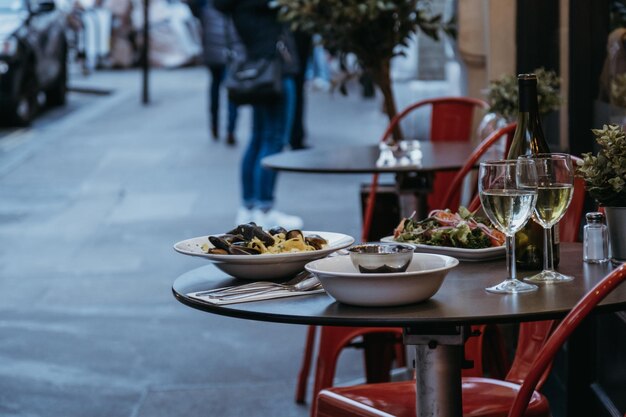 Plates with food and glasses of wine at the outdoor table of a restaurant selective focus