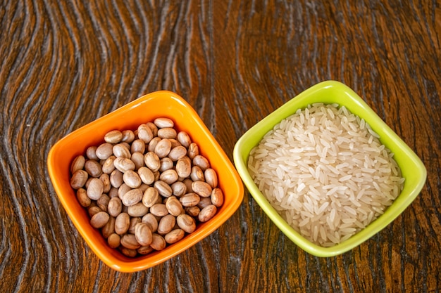 Plates with grains of white rice and beans on wooden table