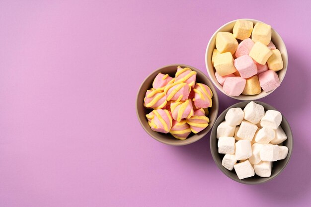 Plates with sweet airy soft marshmallows on the background very peri top view copy space