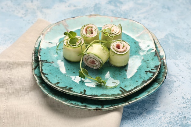 Plates with tasty cucumber rolls on color