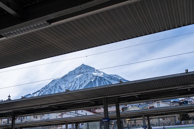 Piattaforma alla stazione ferroviaria con sfondo di montagna innevata svizzera