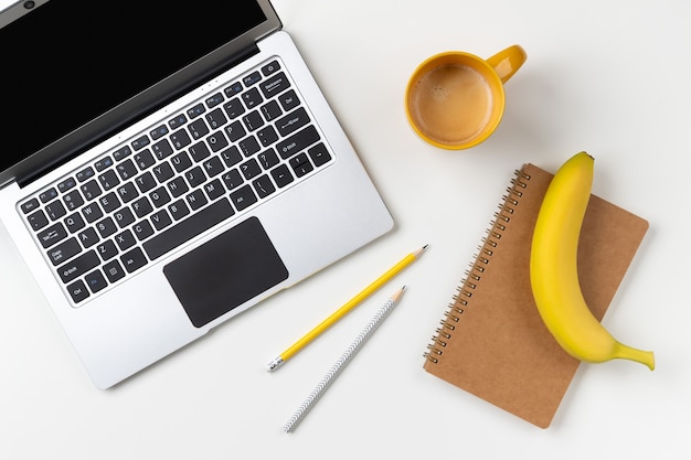 Platliggend bovenaanzicht modern laptopvoedsel en briefpapier op witte tafel