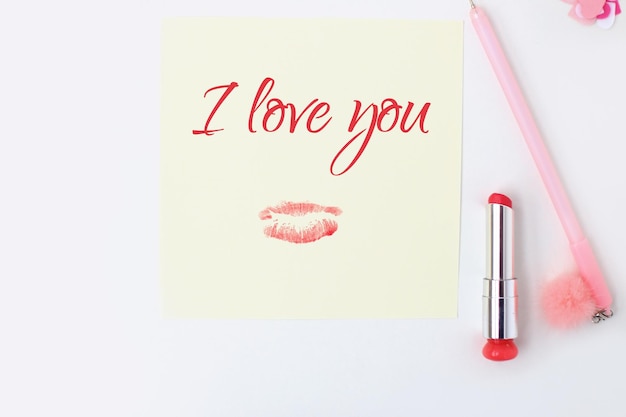 Platliggend geel papier roze pen pompon lippenstift confetti hartjes lip print ik hou van jou tekst Ansichtkaart in envelop maken voor ValentijnsdagDoe het zelfFoto uit de serie