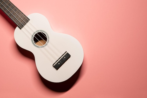 platliggend geschoten met een schattige kleine witte ukelele hawaiiaanse gitaar met nylon snaren op een pastelroze