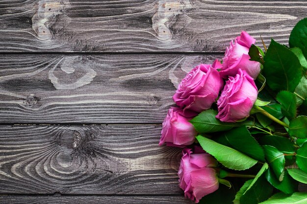 Platliggende ansichtkaart met plaats voor uw tekst. Boeket van roze rozen op een houten donkere achtergrond.