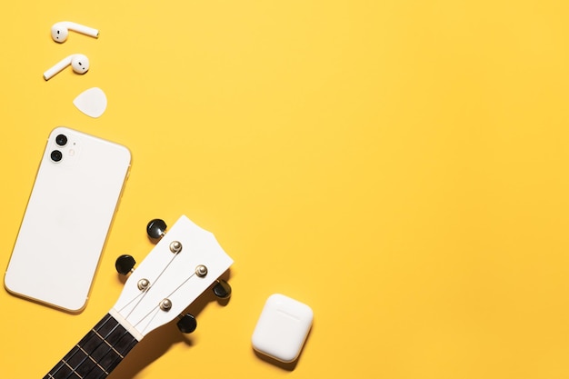 Platliggende compositie met een kopie ruimte op een gele achtergrond met een witte ukelele toets