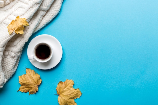 Platliggende compositie met kleurrijke herfstkop koffie en bladeren op een bovenaanzicht in kleur als achtergrond