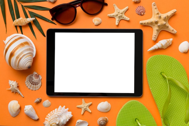 Platliggende compositie met tablet en strandaccessoires op gekleurde achtergrond Tabletcomputer met leeg schermmodel met kopieerruimte