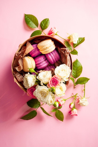 Platliggende ronde papieren geschenkdoos met smakelijke vanille en bosbessen bitterkoekjes op een inpakpapier Een bos mooie rozen die de doos versieren lichtroze achtergrond