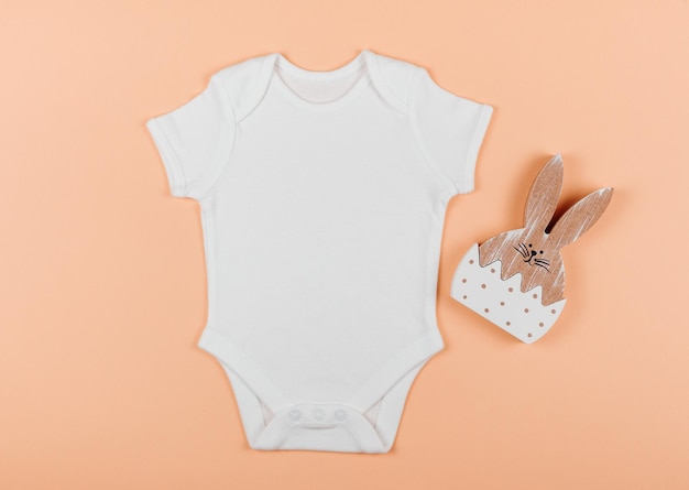 Platte baby schattige witte bodysuit met houten speelgoed Oranje achtergrond Babykleding Mock up