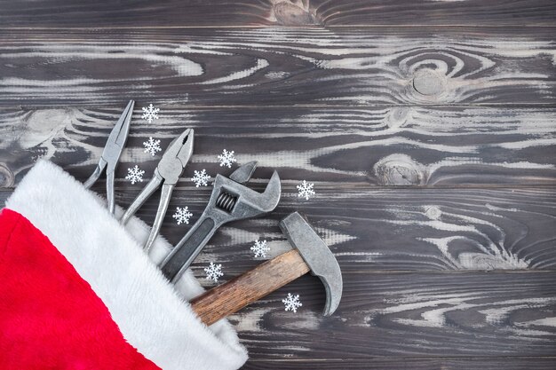 Platte compositie met bouwhulpmiddelen in Kerstman hoed op houten achtergrond. Het concept van Nieuwjaar en Kerstmis in de bouwsector. Bovenaanzicht. Plat. Ruimte kopiëren