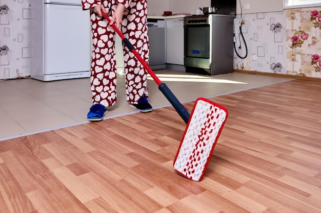 Platte dweil met microvezelpad gebruiken om de vloer in de keuken te dweilen tijdens huishoudelijk werk