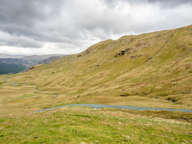 Plattelandslandschapsmening van groen gebied en bergachtergrond onder bewolkte hemel in Engeland