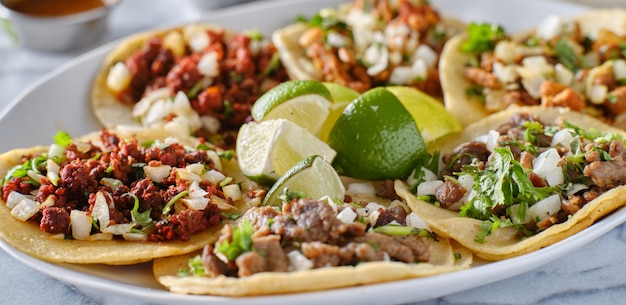 Photo platter of mexican street tacos with carne asada, chorizo, and al pastor in corn tortillas