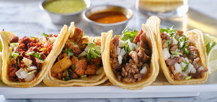 Photo platter of mexican street tacos with carne asada, chorizo, and al pastor in corn tortillas