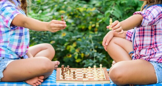 Play chess Sisters playing chess Children play chess outdoors nature background Sport and hobby concept Strategy concept Cognitive development Intellectual game Make decision Smart children