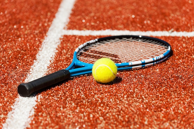 Play tennis? Close-up of tennis racket and tennis ball laying on the court