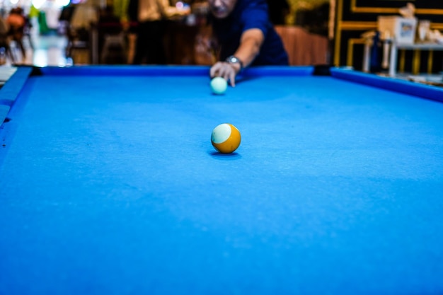 Player aiming cue in a billiard ball. Blurred person in the background