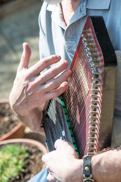 Foto suonatore di autoharp strumento musicale a corde pizzicate, appartenente alla famiglia dei cordofoni.