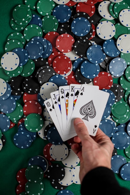 The player holds five playing cards in his hand.Poker Royal Flash on cards and poker chips on casino