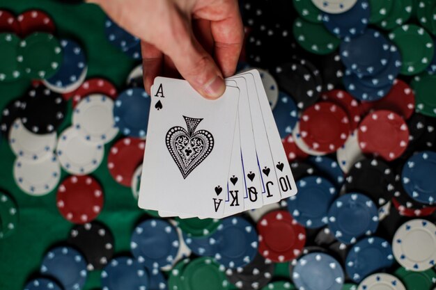 Photo the player holds five playing cards in his hand.poker royal flash on cards and poker chips on casino