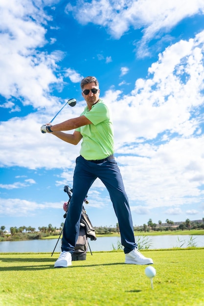 A player playing golf on a golf course hitting the ball next to a lake