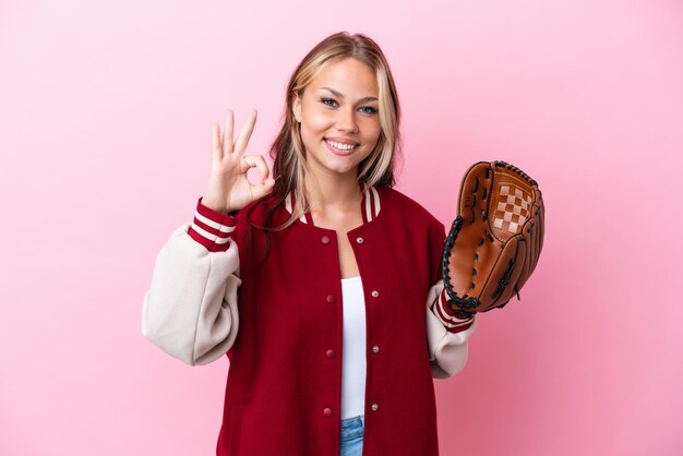 Player Russian woman with baseball glove isolated on pink background showing ok sign with fingers