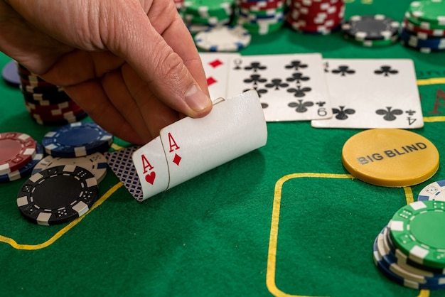 プレーヤーは、チップを備えたカジノの緑のテーブルに2つのトランプエースを表示します
