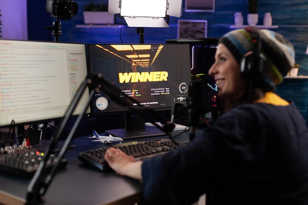 チャット付きのライブストリームでプレーヤーが勝つビデオゲーム。 hmicrophoneとヘッドフォンを備えたコンピューターでオンラインでゲームプレイをストリーミングする女性。彼女がビデオゲームをしている間に放送している人。