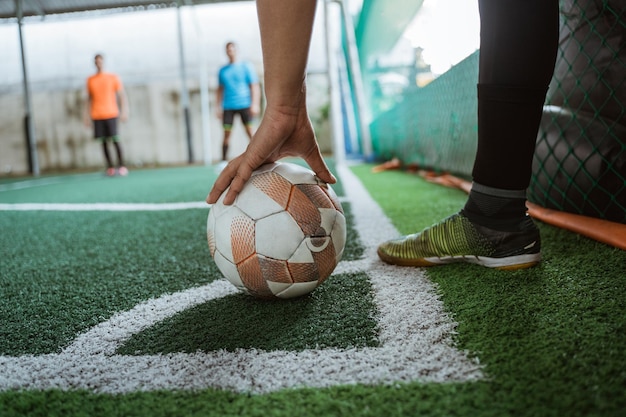 Photo the players hand holding the ball takes a corner kick