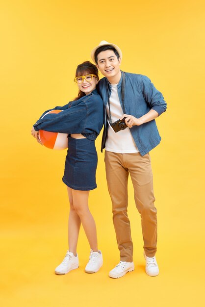 Playful Asian couple in summer casual clothes with beach accessories studio shot isolated