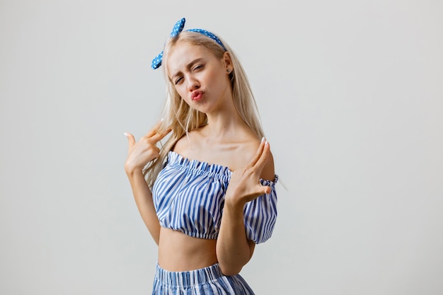 Playful beautiful blonde girl in summer outfit isolated