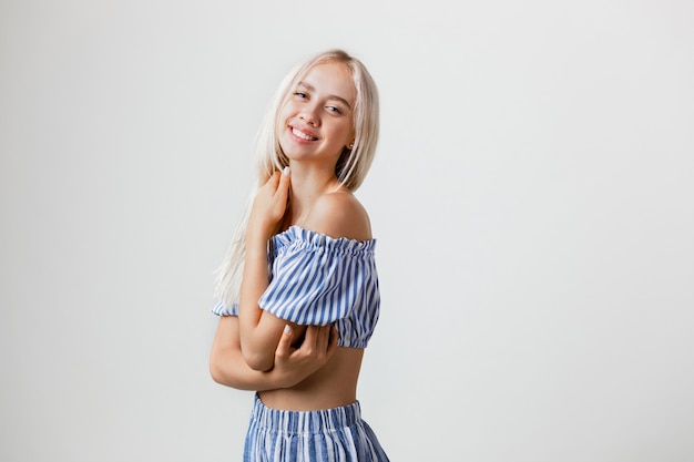 Playful beautiful blonde girl in summer outfit isolated