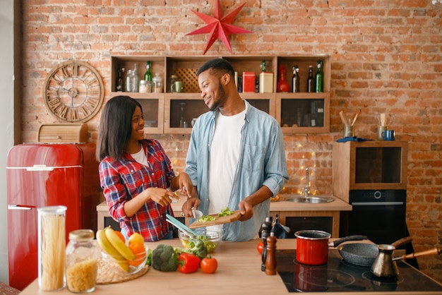 Playful black couple cooking dinner on the kitchen