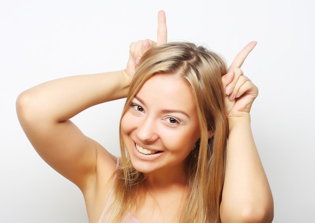 Playful blond girl shows horns