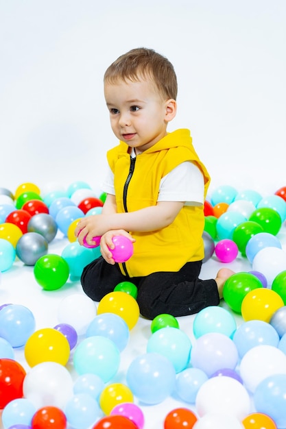 Ragazzo giocoso che si diverte nel parco giochi ragazzino che gioca con palline colorate