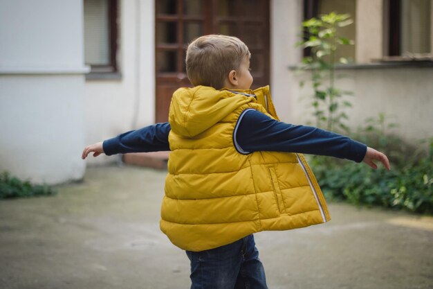 Photo playful boy walking against house